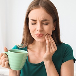 Woman experiencing tooth sensitivity from coffee