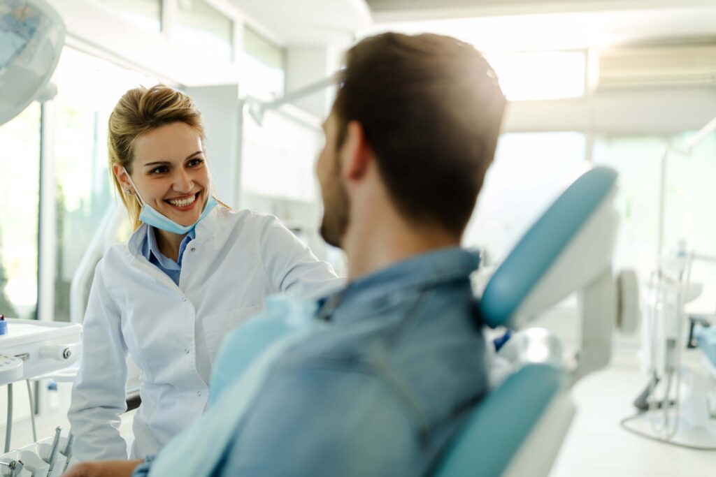 Smiling dentist talking to patient in treatment chair